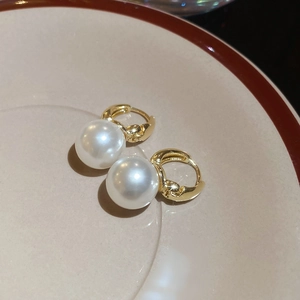Detailed view of elegant round pearl drop earrings with polished gold leverback closures