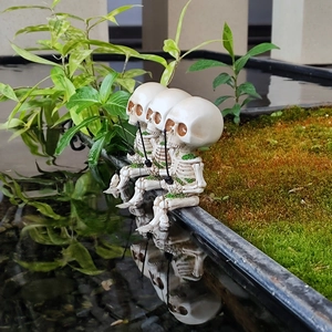 Macro view of three resin fishing skeletons with green moss details for Halloween decor