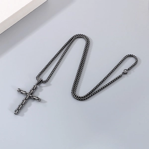 Detail of a vintage black stainless steel cross pendant on a beaded box chain necklace