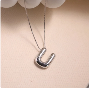 Macro shot of 3D silver bubble initial U pendant with a polished mirror finish on a chain