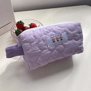 Dettaglio macro della borsa cosmetica trapuntata viola con motivi floreali