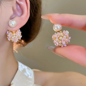 Détail de boucles d'oreilles fleurs roses avec perles blanches et finition dorée élégante