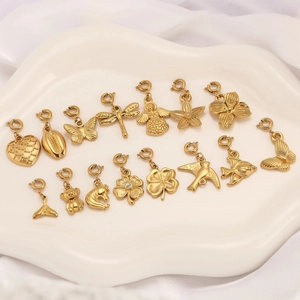 Golden stainless steel ocean and insect charms set on a white ceramic plate