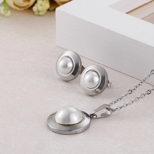 Elegant silver-toned necklace and earrings set with round white pearls on textured background