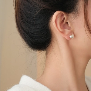 Detail of heart-shaped pearl earring worn by model showing iridescent white luster
