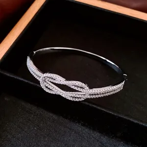 Bracelet nœud en argent plaqué or 18 carats avec zircons pavés sur présentoir noir