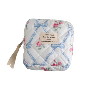 Quilted white floral cosmetic bag with pink roses, blue bows and ribbon zipper pulls