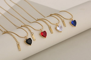 Detailed view of colorful heart crystal necklaces on gold snake chains in various hues