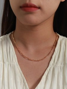 Detail of rose gold minimalist chain necklace on model's neck with textured white top