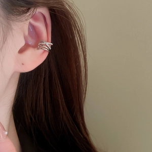 Close-up of a silver crisscross layered ear cuff with zircons worn on model ear