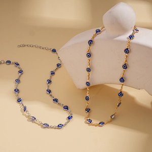 Detail of gold and silver Evil Eye necklaces with blue enamel beads and extension chains