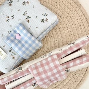Close-up of floral fabric book covers with heart buckles on a woven mat surface