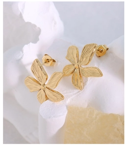 Macro view of gold flower earrings with brushed texture and metal bead center details