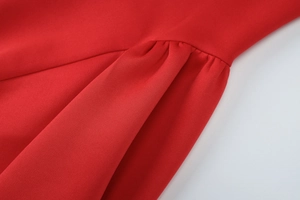 Detailed macro view of the ruched seam design on a red bodycon cocktail dress