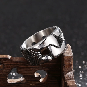 Macro shot of vintage silver chain ring with hollow portrait carving on wood base