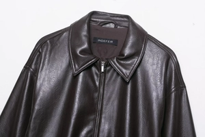 Detailed view of deep brown faux leather jacket texture and metallic zipper on collar
