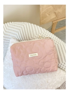 Gros plan détaillé du sac cosmétique matelassé rose avec coutures florales et logo