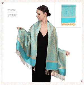 Detailed close-up of teal cashmere shawl with gold paisley patterns and fringed edges