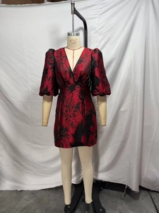 Détail du tissu jacquard floral rouge sur une robe courte à col en V et manches bouffantes