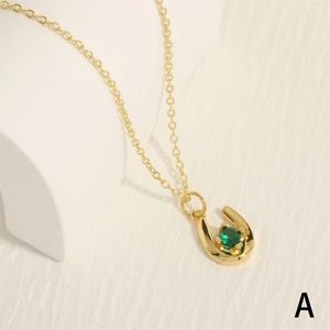 Close-up of horseshoe pendant necklace with green zircon stone and gold-plated chain