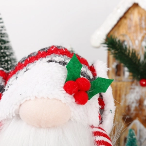 Macro detail of Christmas gnome showing knitted red hat with holly leaf and berry accents