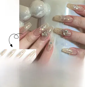 Detailed view of long coffin press-on nails with nude pink base, silver glitter, and heart rhinestones