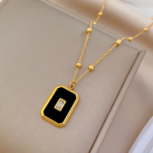 Detail of gold titanium steel ball chain with black square pendant and sparkling zircon