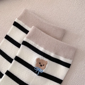 Gros plan sur les rayures et la broderie d'ours des chaussettes mi-mollet pour femmes