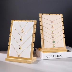 Bamboo and leather necklace display stand holding multiple gold pendant jewelry pieces