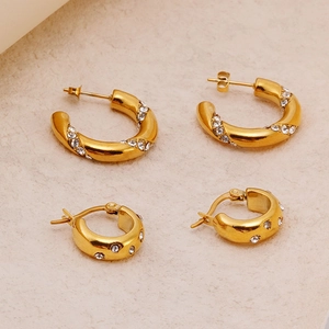 Boucles d'oreilles C en acier doré ornées de zircons brillants sur fond blanc