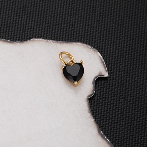 Gold-plated heart pendant with black zircon stone on white paper for jewelry making