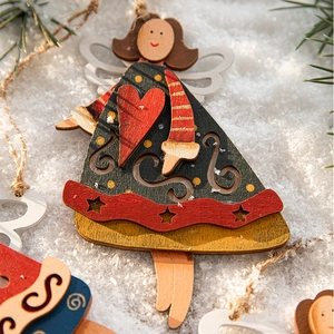Creative hand-painted wooden Christmas angel pendant hanging on a festive snowy pine tree