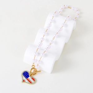 Macro shot of pearl necklace with USA flag heart pendant and shiny rhinestones