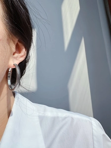 Detail of silver spring spiral hoop earrings with polished metal texture on model