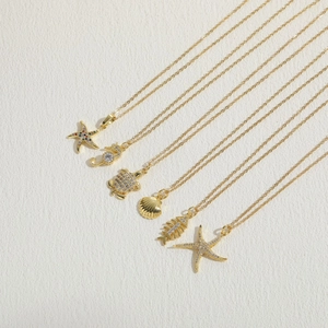 Ocean themed necklace set featuring gold starfish, seahorse, turtle, and shell pendants