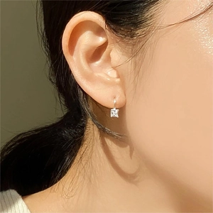 Close-up of square zircon stud earrings in 925 sterling silver worn on ear