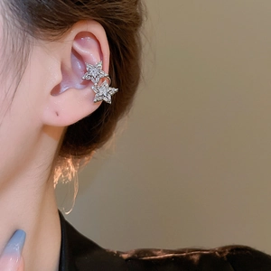 Close-up of elegant silver star ear cuff with sparkling zircon crystals on model's ear