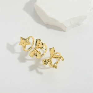 Elegant gold bow and star open adjustable rings displayed on a white decorative stone