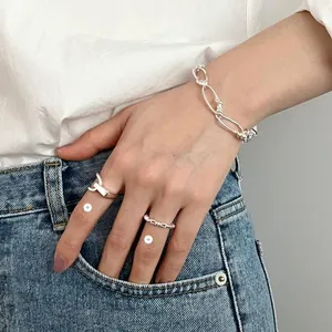 Detail shot of 925 sterling silver chain bracelet and knot rings worn on female hand