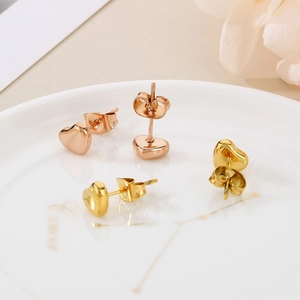 Boucles d'oreilles cœur polies en or et or rose sur un plateau en céramique blanc