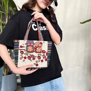 Detail of canvas tote bag featuring embroidered owls and colorful striped handles