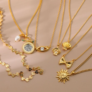Detailed close-up of gold-plated sun, bow and evil eye pendants with pearl accents