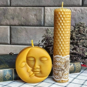 Detail van een zon en maan waskaars met artistiek reliëf en een honingraattextuur