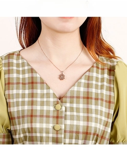 Close-up of rose gold clover pendant with zircon worn on model's neck for elegant look