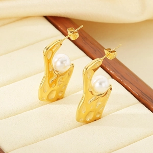 Macro detail of gold irregular geometric earrings with white pearls in velvet box