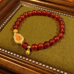 Detail of garnet jasper bead bracelet with gold gourd charm and heart pendant