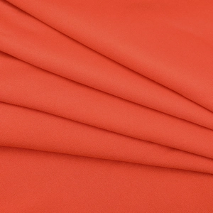 Close-up detail of the orange woven textile fabric with fine texture and soft draping