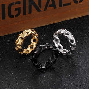 Three punk style titanium steel chain link rings in gold, silver, and black on dark stone