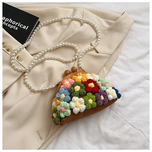 Detail of handmade floral woven shell bag featuring wood clasp and pearl chain strap