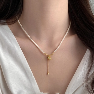 Détail du collier de perles d'eau douce avec pendentif gland doré et zircon sur soie blanche